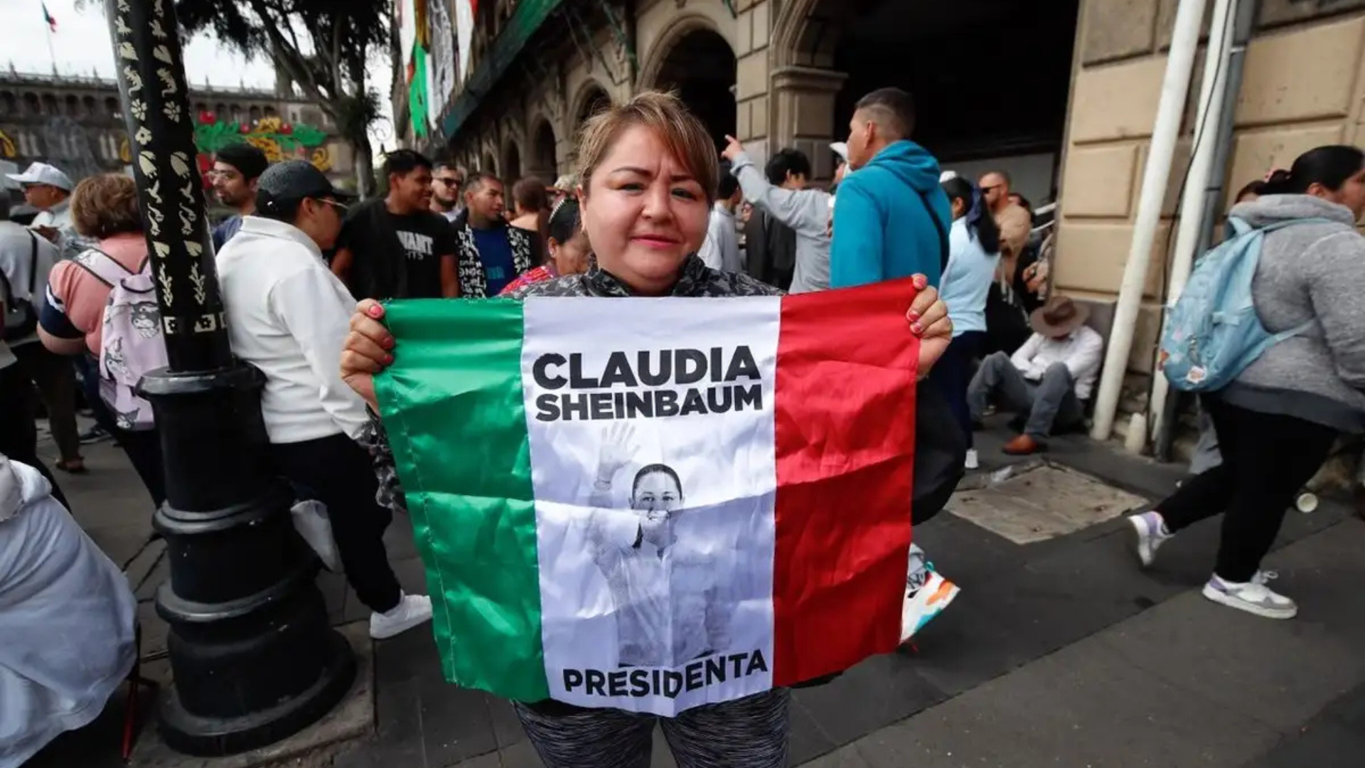 Mujer sostiene una bandera con la imagen de Claudia Sheinbaum durante el acto en el Zócalo