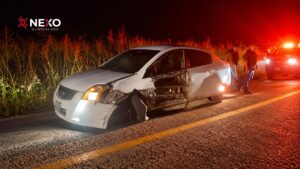 Un automóvil blanco presenta daños en la parte delantera y lateral izquierda tras un accidente carretero ocurrido durante la noche.