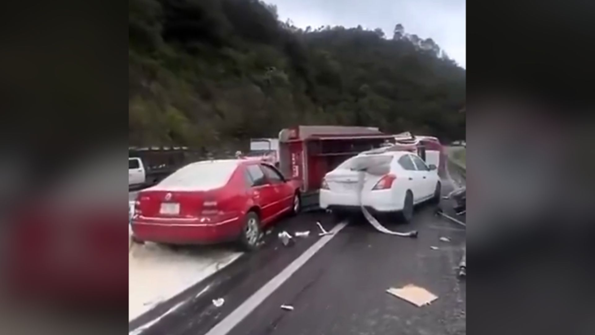 Camión de bomberos volcado detrás de dos automóviles, uno rojo y otro blanco, tras el accidente en Chiapas ocurrido en la autopista San Cristóbal–Tuxtla Gutiérrez.