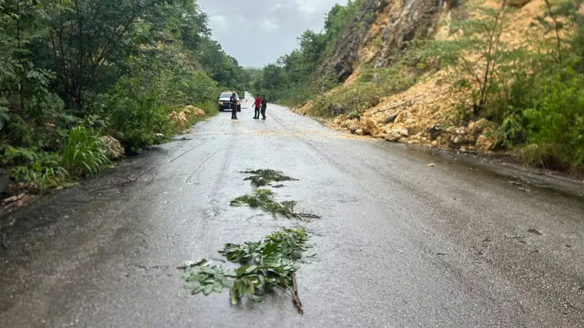 Trabajador de Protección Civil coloca un cono de seguridad sobre la carretera Calderón–Rovirosa tras un deslave en Othón P. Blanco.