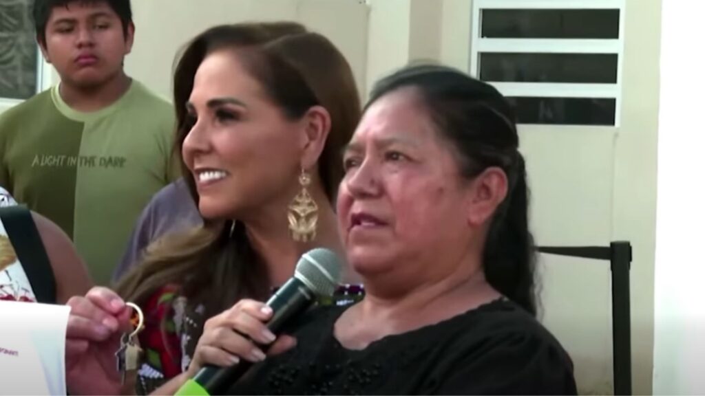 Doña Catalina Álvarez sostiene las llaves de su nueva vivienda mientras Mara Lezama la acompaña en Playa del Carmen.