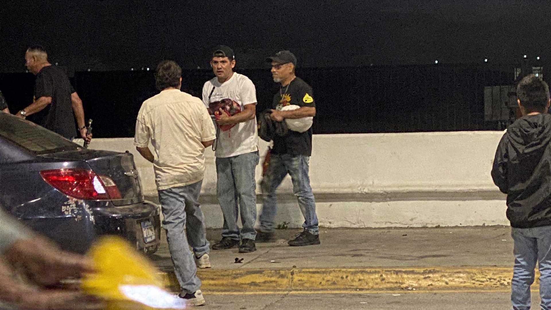 Hombre con playera roja apoyado sobre manos y rodillas en una avenida de Cozumel, con vehículos al fondo