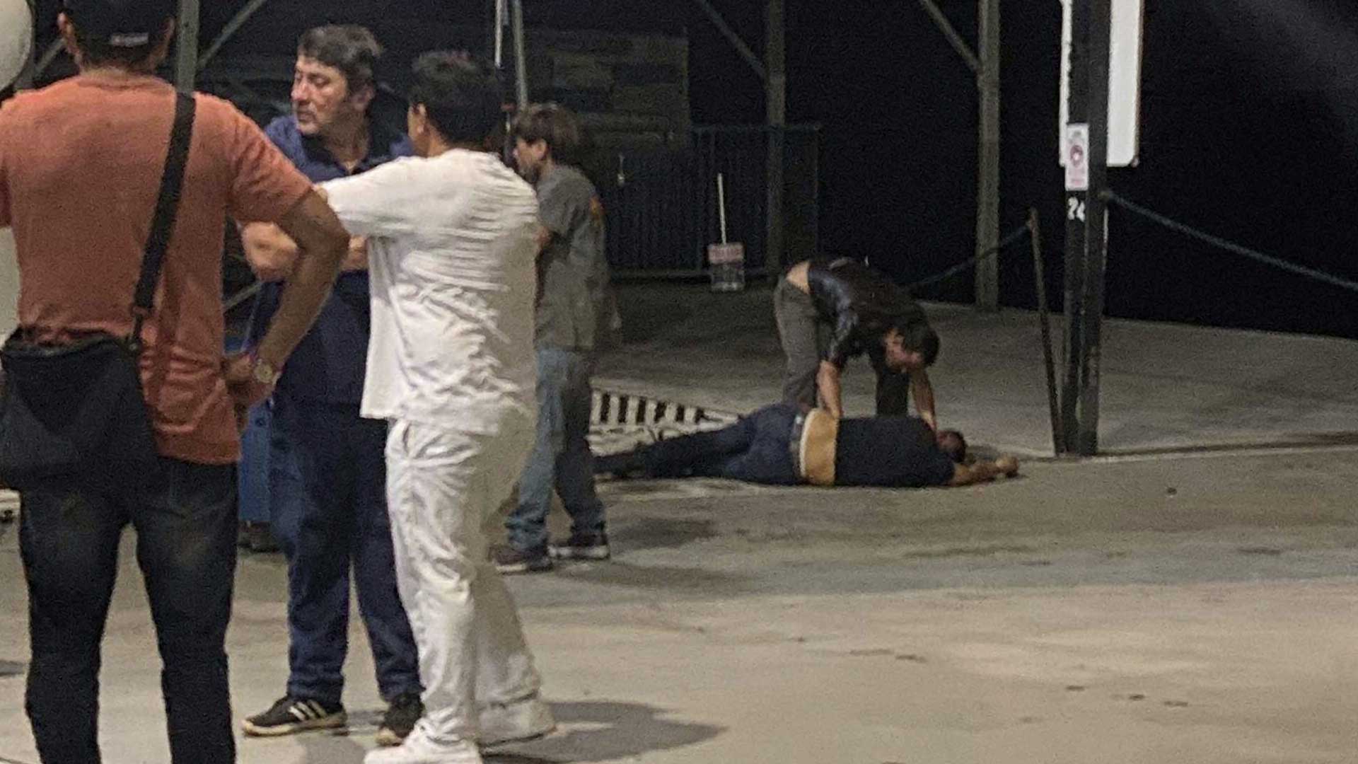 Hombre apoyado sobre manos y rodillas en el pavimento del malecón de Cozumel durante la noche