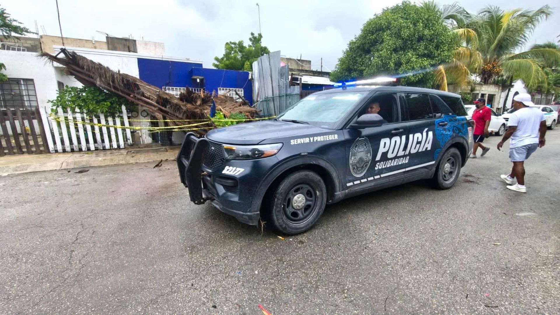 Patrulla de la Policía Municipal junto a una palapa desplomada y acordonada en Misión de las Flores, Playa del Carmen.