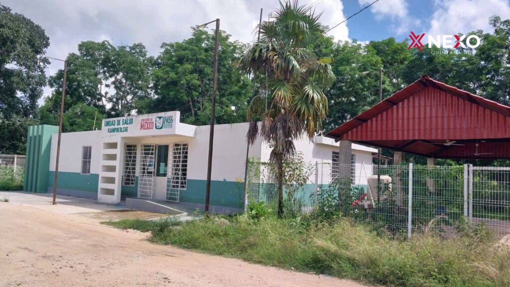 Vista exterior de un inmueble de salud en Kampokolché, con fachada blanca y verde, vegetación y una estructura de techo rojo